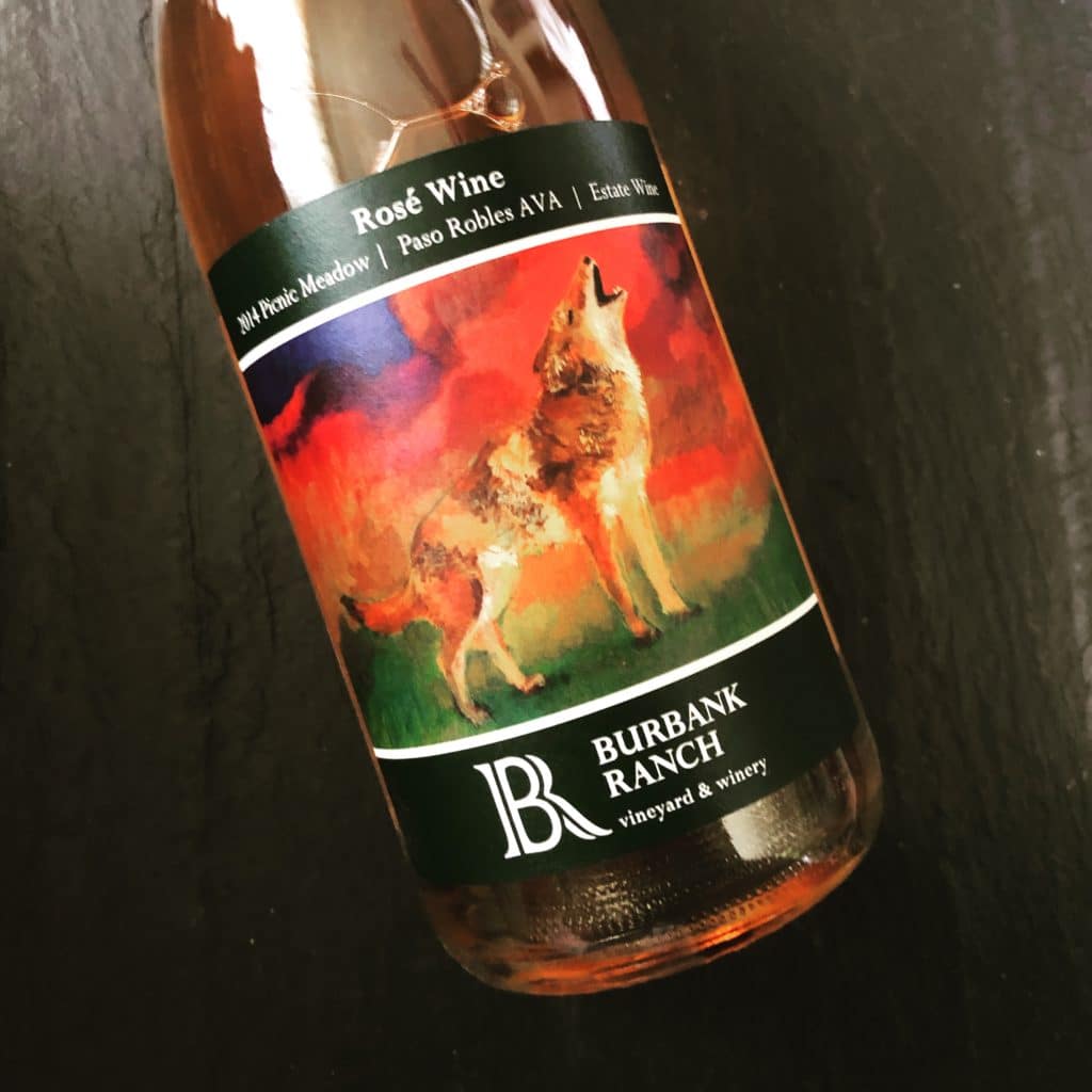 62% Grenache, 38% Mourvedre Copper-hued, Burbank Ranch’s 2014 Picnic Meadow Rosé is citrus driven, with tones of mandarin and orange creamsicle. In the mouth, it continues in that vein, with creaminess at the mid-palate that is tinged in orange pith and white grapefruit. The finish is softly focused, a gentle dwindling of flavor, it’s past its zenith at this point. 13.9% ABV | Sample